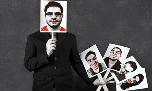 a man holding a set of signs with different faces and expressions on them, with one sign over his face