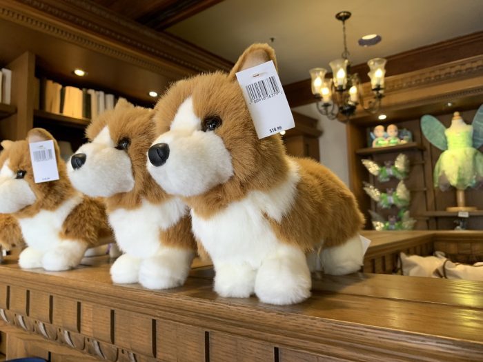 a line of toy stuffed corgi dogs on a shelf, barcode tags attached to their ears